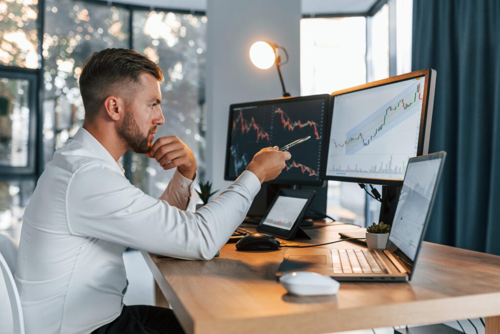 Investor comparing Forex Managed Accounts and Copy Trading strategies on multiple monitors