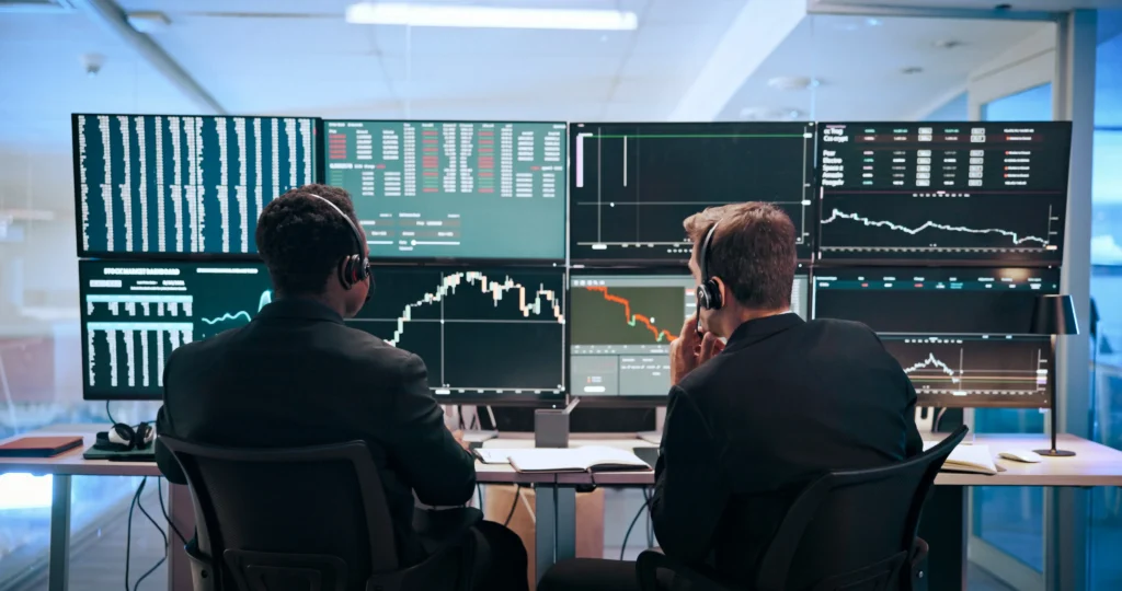 Men review ECN vs Market Maker Brokers on computer for forex trading.