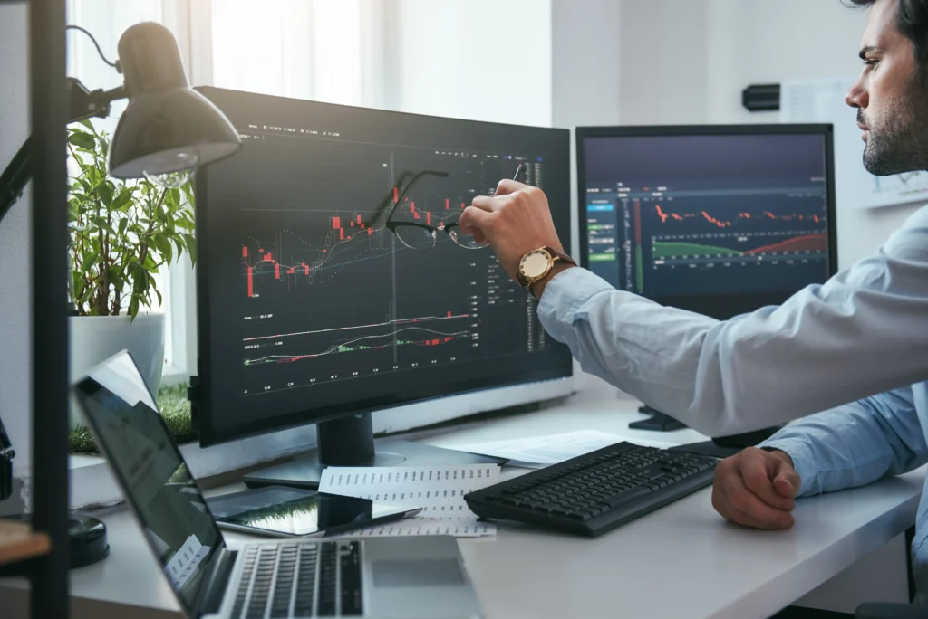 Trader pointing at forex graphs comparing Scalping vs Swing Trading 2025 on computer screen.