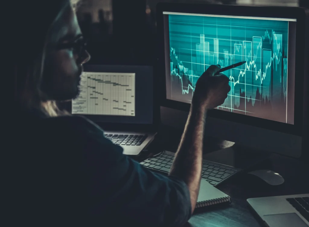 Man working on computer facing the Dark Side of Trading and managing emotional and psychological challenges for long-term success.