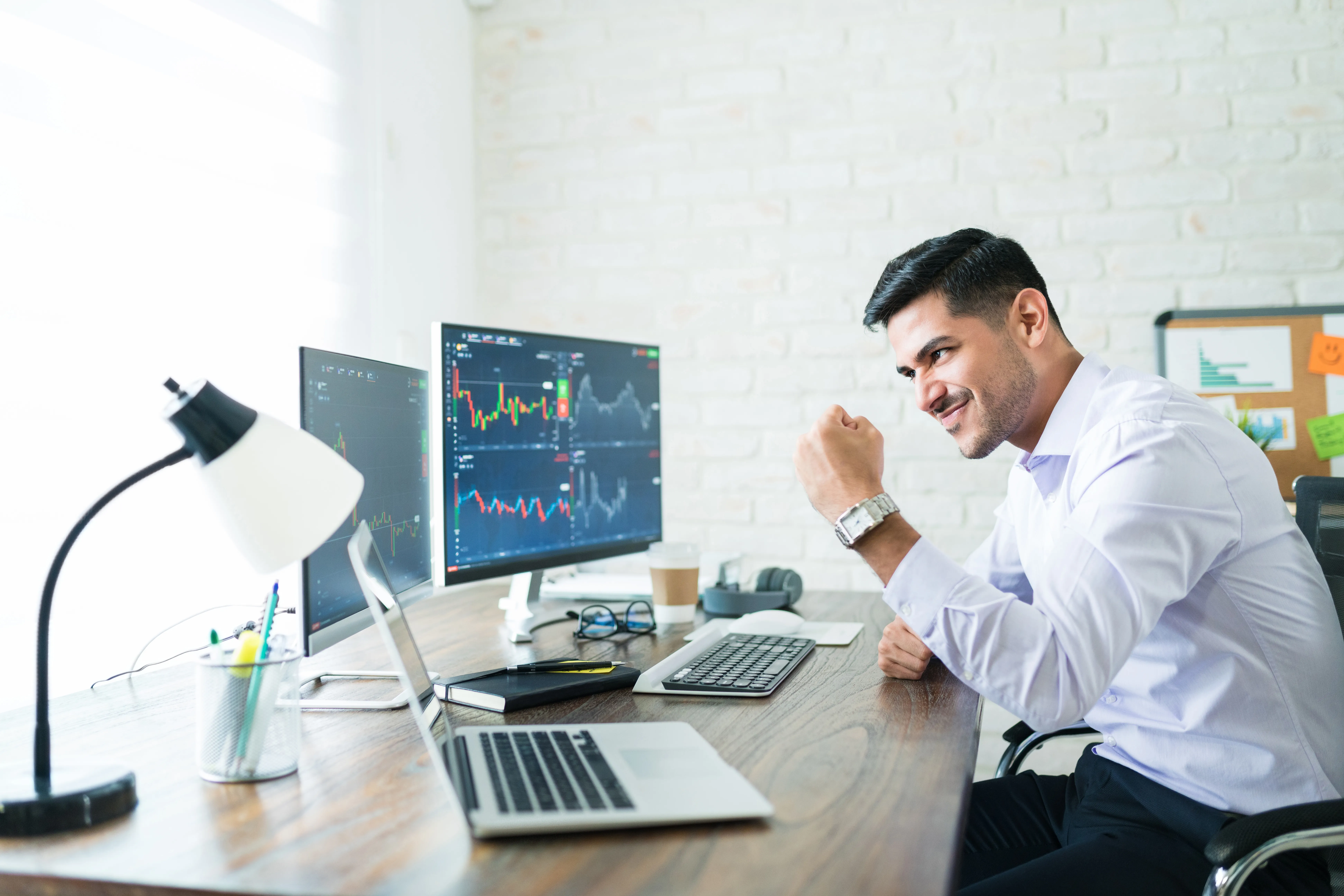 Trader celebrating with charts on screen.