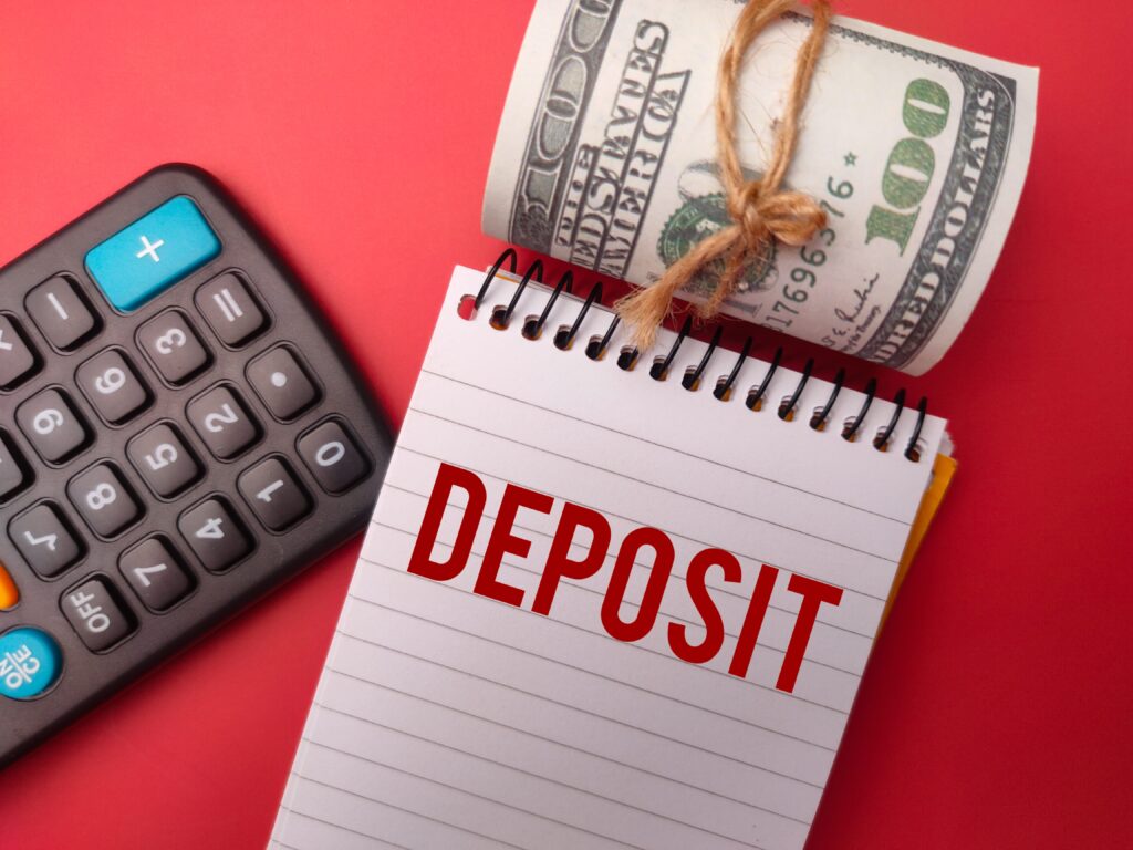 Calculator, banknotes, and notebook labeled DEPOSIT on red background showing Fixed Deposit Interest Taxation concept.