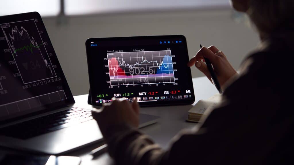 Trader monitoring forex charts on tablet and laptop, learning how to track pips accurately in real time.