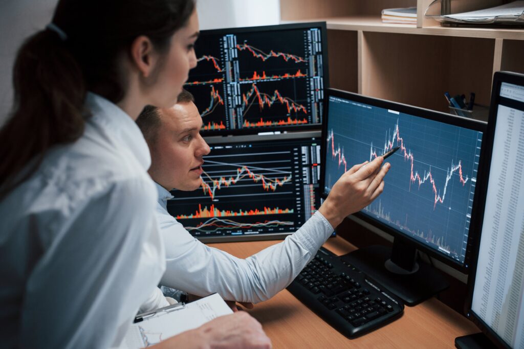 Traders discussing hidden candlestick patterns on multi-screen chart setup