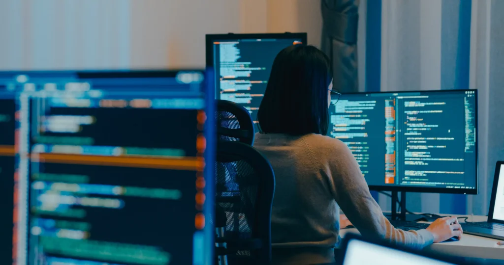 Person working on backtesting with trading data displayed on multiple monitors.