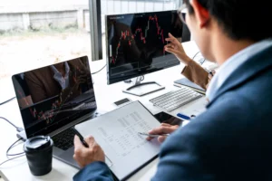 Traders analyzing spot trading charts and financial data on computer screens in an office setting.
