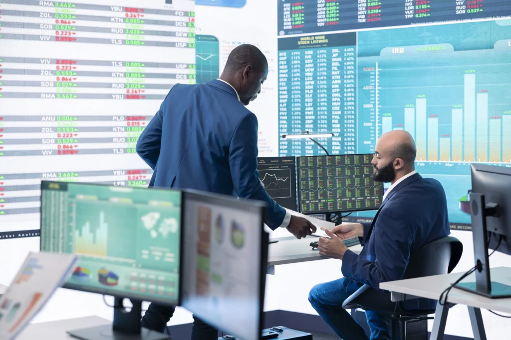 Financial professionals reviewing market sentiment indexes on trading monitors in an office setting.