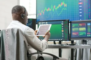 Trader using tablet and monitors for quantitative trading analysis