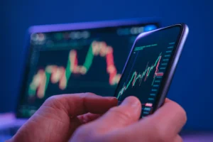 Hand holding phone with trading momentum divergence chart displayed.