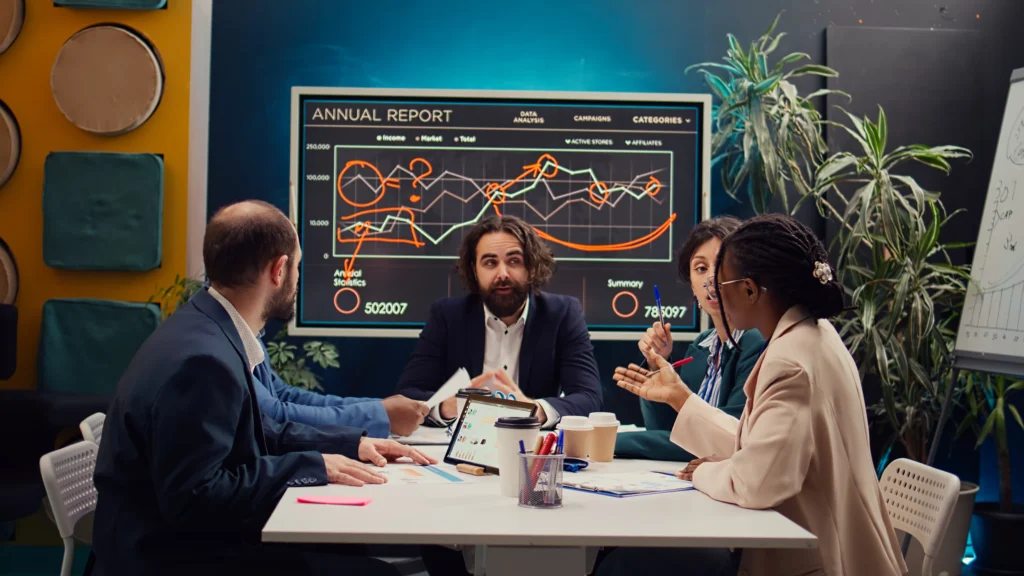 Team reviewing trading strategy graphs during a Trader vs Strategy business meeting in a modern office setup.