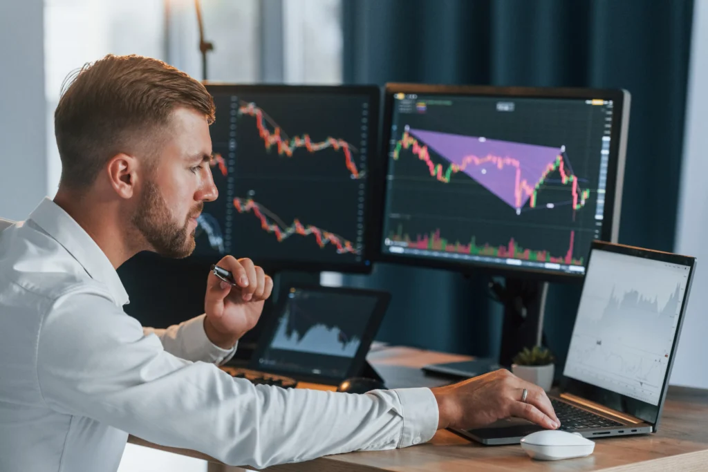 Trader analyzing Head and Shoulders Pattern on financial charts at a multi-screen workstation