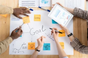 Teamwork and brainstorming session with notes and charts focused on Forex Trading Goals.