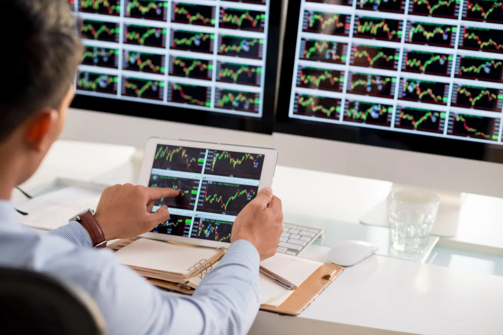 Trader analyzing forex charts on tablet and monitors with Adaptive AI in Multi-Timeframe Trading for smarter execution in 2025.