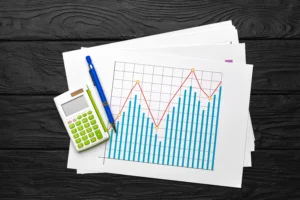 Line graph with bars and red trend line on paper next to calculator and pen for data analysis.