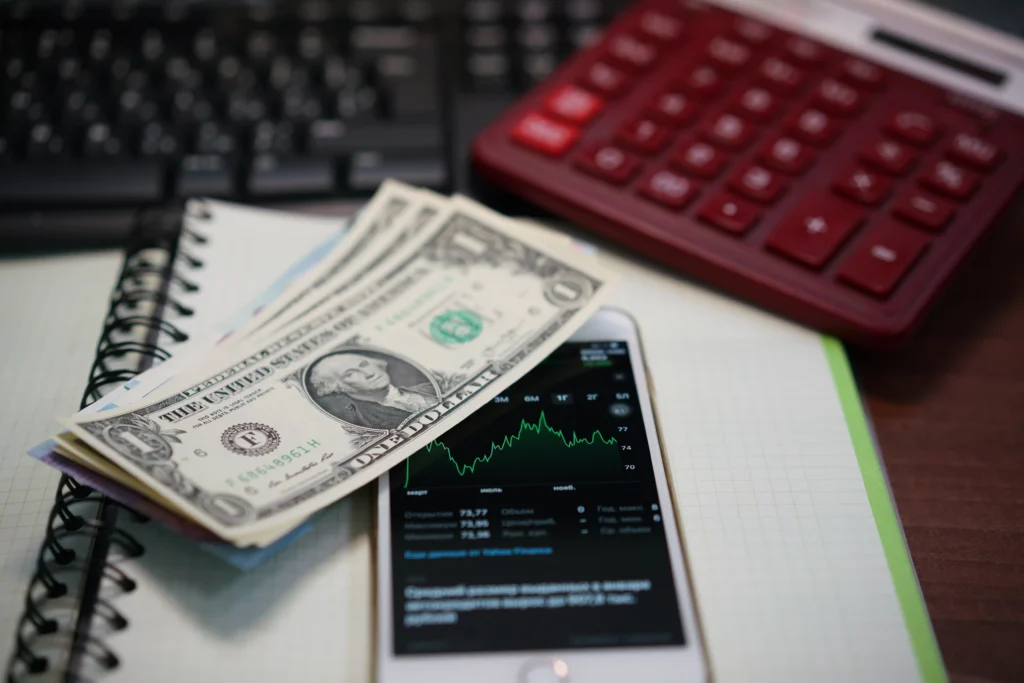 Cash-and-Carry Trade concept with dollars, stock chart, and calculator on desk.
