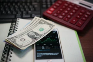 Cash-and-Carry Trade concept with dollars, stock chart, and calculator on desk.