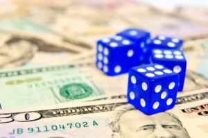 Blue dice on dollar bills symbolizing risk and decision-making in prediction markets