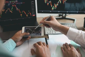 Traders analyzing moving average crossover charts on laptop and phone to study Golden Cross vs Death Cross signals."