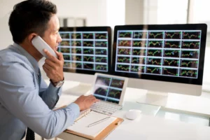 Trader at desk studying forex and stock charts, showing cognitive biases in trading analysis.