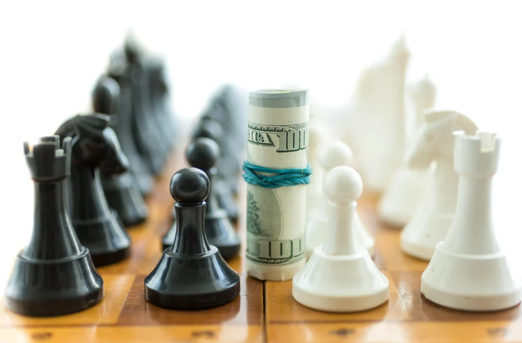 Chess pieces and a rolled dollar bill representing the Negative Reward Risk Strategy in trading decisions