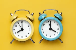 Morning vs Evening Trading Routine visual with yellow and blue alarm clocks on yellow background.
