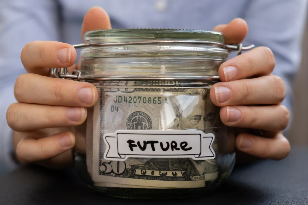 Hands holding a glass jar of money labeled future, representing how to trade futures and plan investments in 2025.