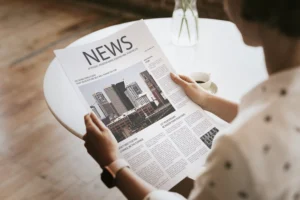 Woman reading a newspaper to monitor the first 15 minutes after major news for trading opportunities.