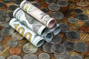 Rolled US dollar bills and scattered coins symbolising smart money activity, liquidity flow, and institutional influence in forex trading.