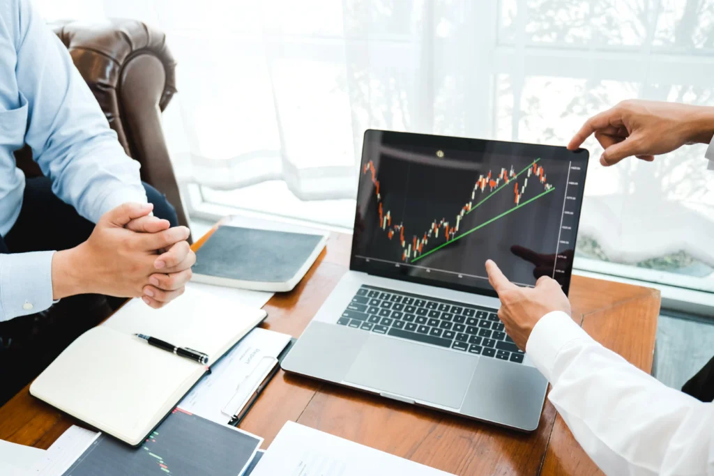 Businessmen analyzing the bear flag pattern in trading on a laptop chart during a forex and stock market strategy meeting.