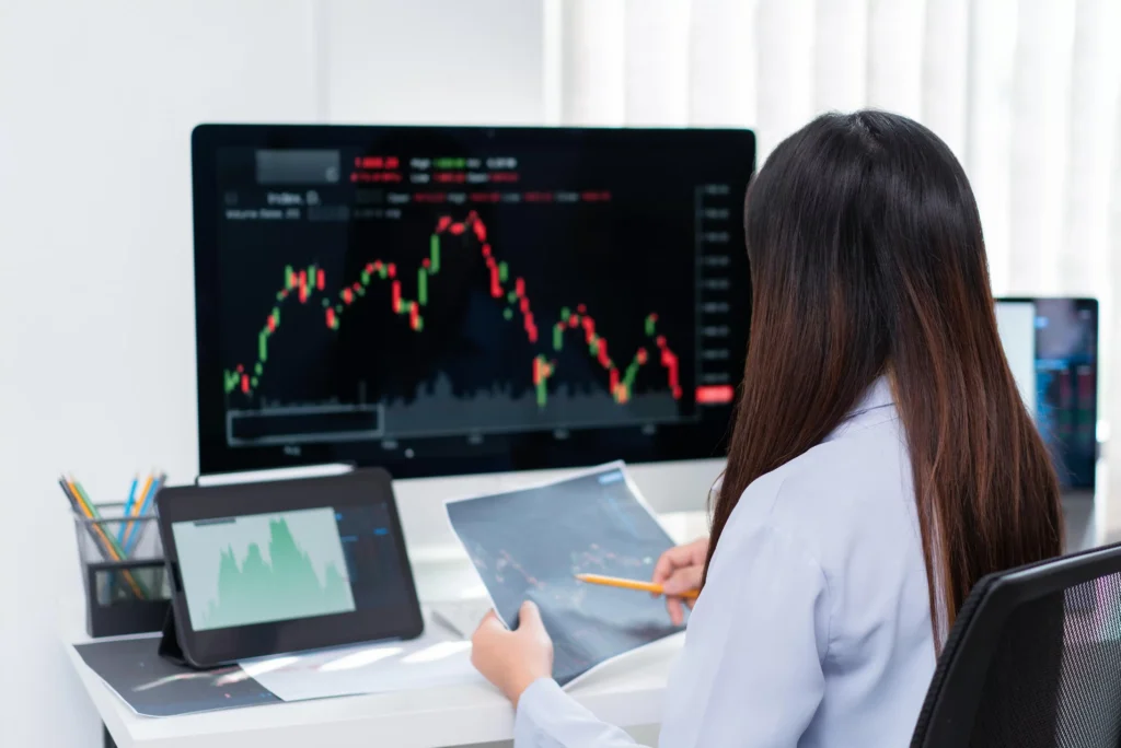 Trader analyzing candlestick charts on computer and tablet to identify Supply & Demand Zones for forex trading strategy.