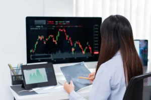 Trader analyzing candlestick charts on computer and tablet to identify Supply & Demand Zones for forex trading strategy.