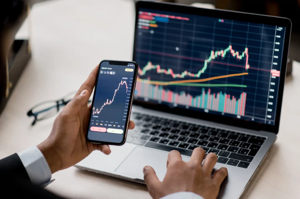 Forex trader analyzing price charts on laptop and smartphone — SMC vs ICT trading strategies in 2025.
