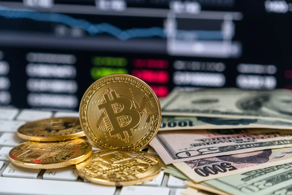 Bitcoin coins placed on a keyboard beside U.S. dollar bills, symbolizing Forex vs Crypto trading comparison.