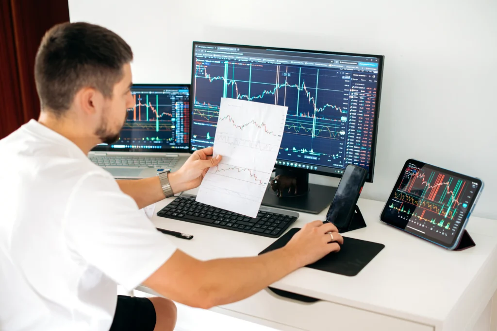Trader analyzing Fibonacci retracement trading strategies on multiple screens with forex charts
