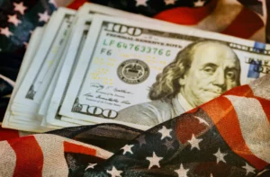 Stack of U.S. $100 bills wrapped in the American flag during the $7.1 Trillion Wealth Surge.