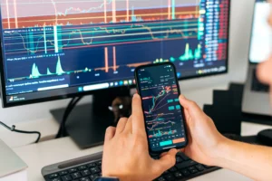 Trader analyzing complex adaptive systems in trading on smartphone and monitor with charts and technical indicators in 2025.