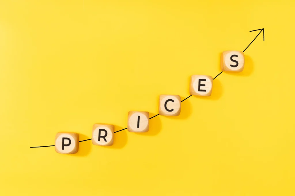 Unchanged Prices concept with wooden blocks spelling PRICES on yellow background and arrow line showing market direction.