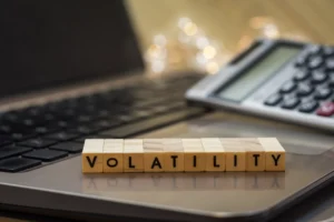 Wooden blocks spelling volatility on laptop with calculator symbolizing forex volatility indicators and financial risk measurement in 2025