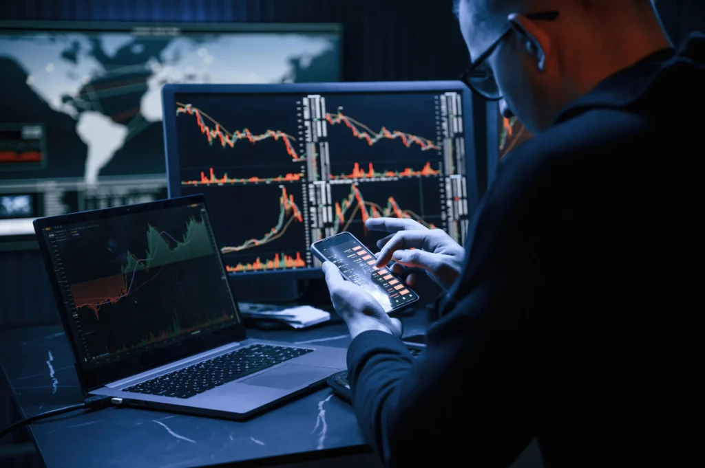 Trader analyzing forex charts with liquidity zones and order blocks on multiple screens while executing trades on a smartphone in 2025.