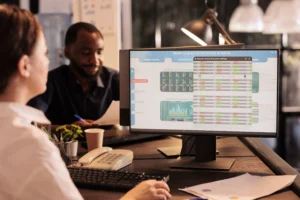 Traders analyzing market data and financial statistics on screen while discussing CFD Trading strategies in an office environment.