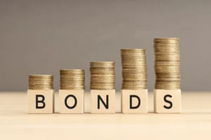 Stacks of gold coins arranged over wooden blocks spelling the word Bonds.