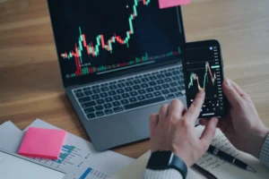 Trader analyzing live forex charts on laptop and smartphone while applying the 1-Minute Scalping Strategy for real profits in 2025.