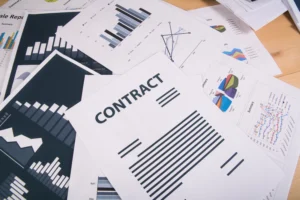 A desk covered with business reports, charts, and a contract sheet symbolizing CFD trading analysis and strategy planning in 2025.