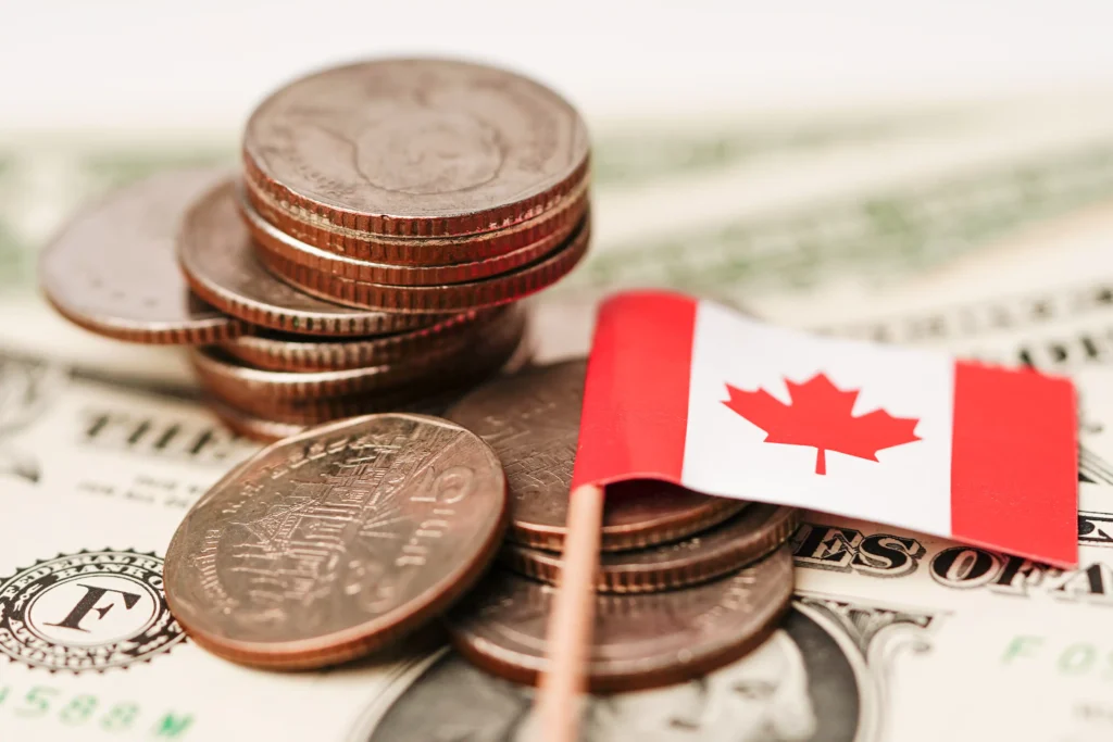 Canadian coins with a flag on U.S. dollars showing the Canada economic collapse in 2025.