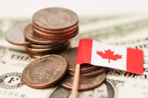 Canadian coins with a flag on U.S. dollars showing the Canada economic collapse in 2025.