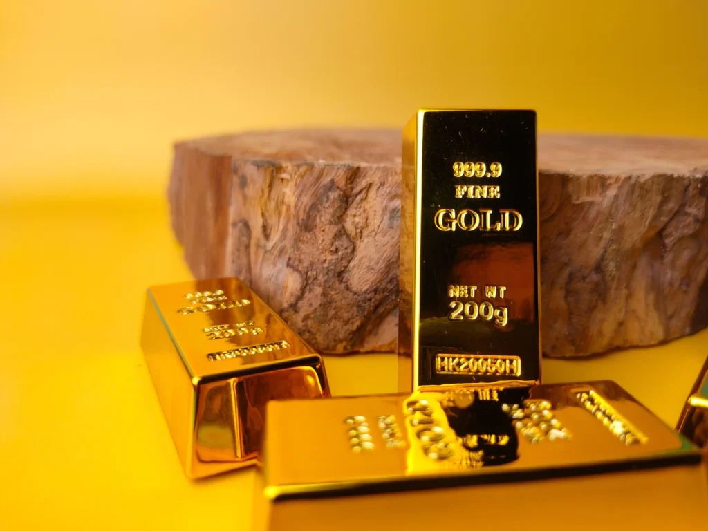 Gold bars stacked on a yellow surface beside a wooden base symbolizing value and stability