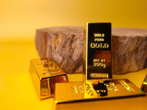 Gold bars stacked on a yellow surface beside a wooden base symbolizing value and stability