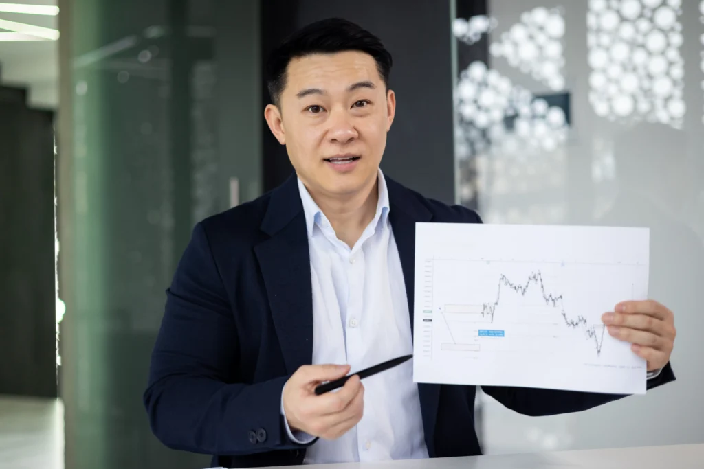 Man in business attire presenting a financial chart showing market trend analysis.