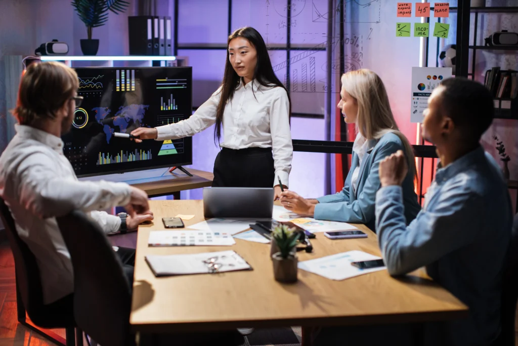 Group of professionals analyzing market charts on a screen, demonstrating the application of the Supertrend Indicator Strategy for trading decisions.