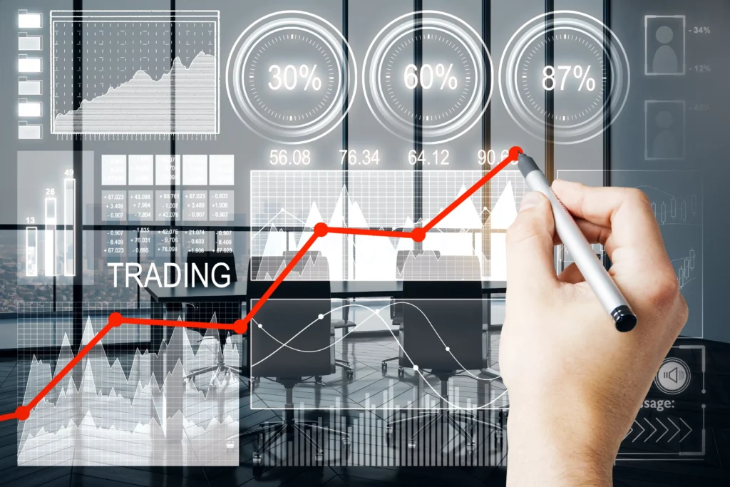 A person drawing a rising red trading line on a transparent digital screen showing stock market graphs, charts, and analytics.